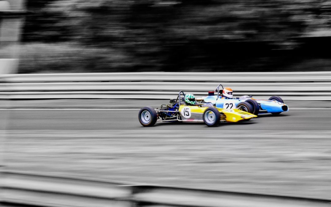 Two old formula 1 cars racing are in color with black and white background